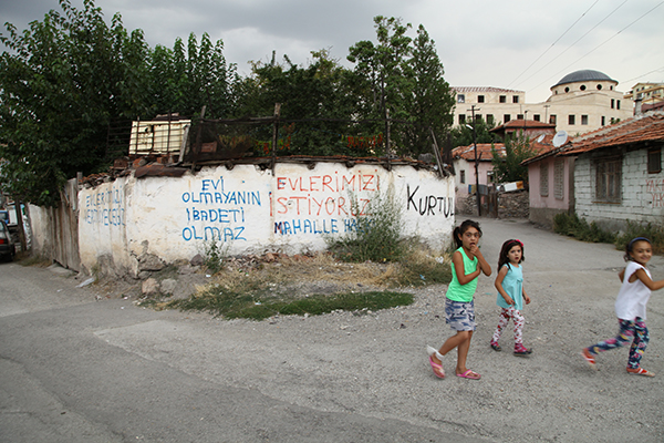 Barınma hakkı mücadelesinin yürütüldüğü Kartaltepe Mahallesi, yaklaşık bir yıldır da Cami-Cemevi Direnişi'ne ev sahipliği yapıyor. Mahallenin envai çeşit boşluğuna yapılan yazılamalar ve arkalarından yükselen Cami-Cemevi aynı karede görülebiliyor. Kartaltepeliler, projeye karşı sözlerini de duvara yazmış: "Evi olmayanın ibadeti olmaz"